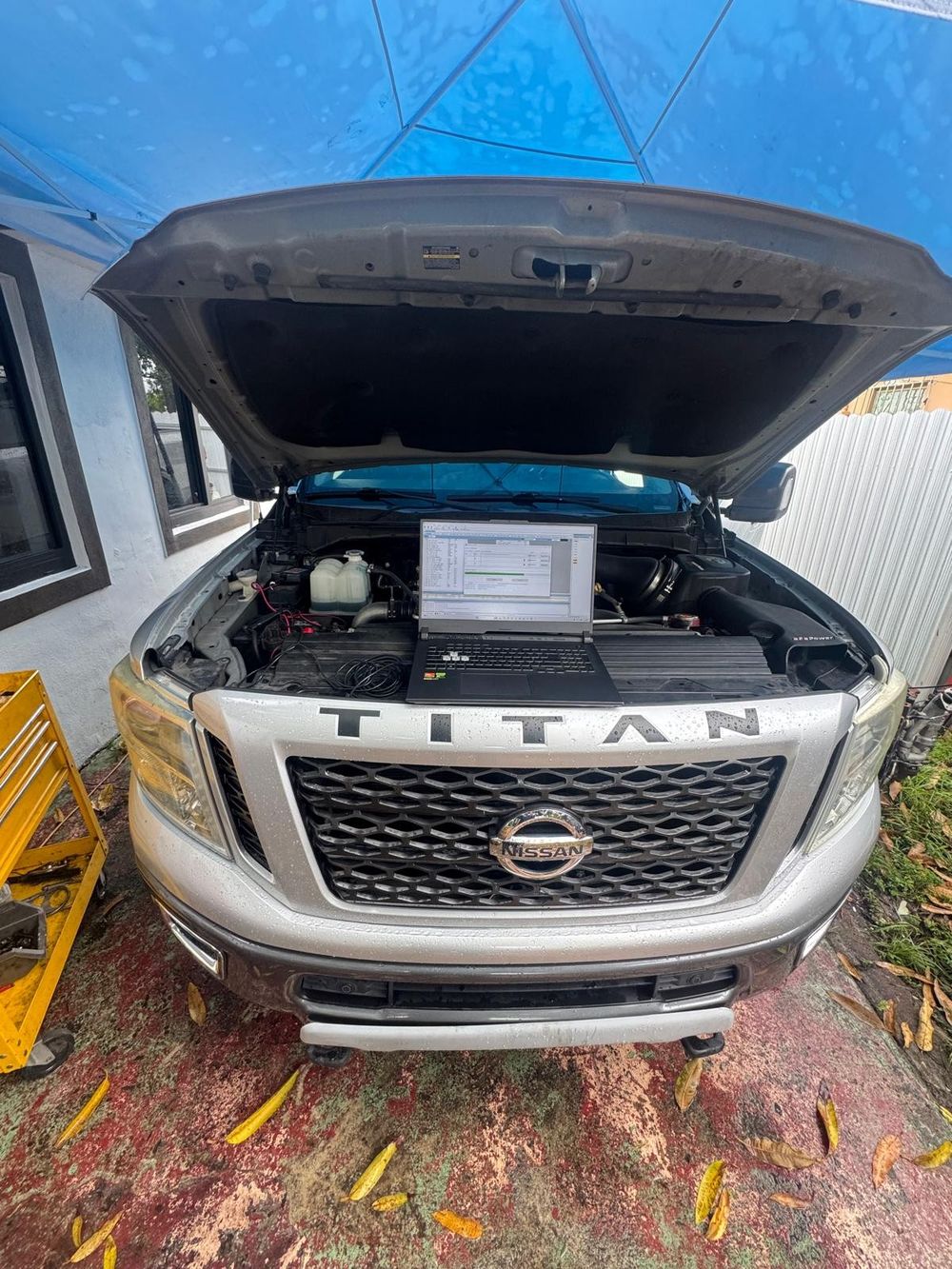 Diagnóstico de pickup diésel Nissan Titan con laptop sobre el motor